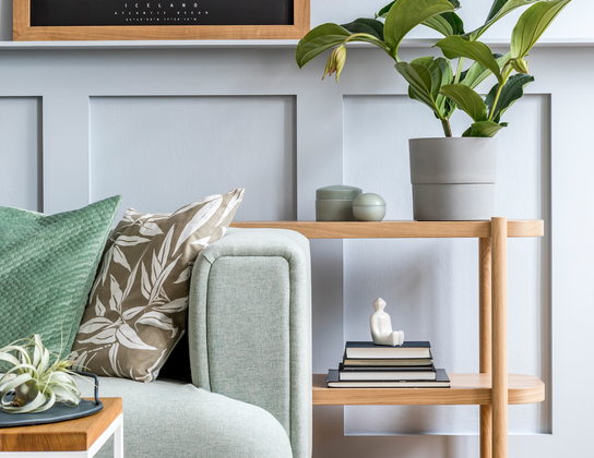 Woonkamer met mintgroene bank, houten wandmeubel en plant in een koopwoning in Voorschoten