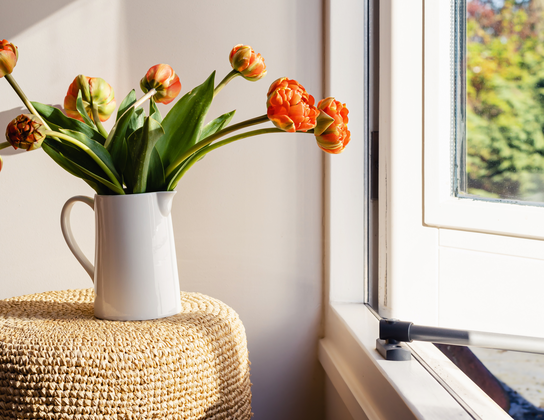 Oranje tulpen in een witte kan bij het raam van een nieuwe koopwoning in Voorschoten