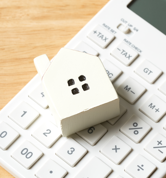 Wit houten huisje op een rekenmachine als symbool voor woningtaxatie in Voorschoten