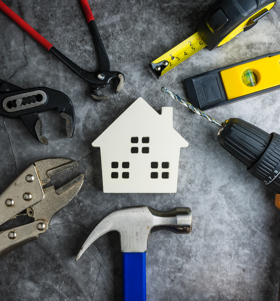 Wit houten huisje omringd door gereedschap als symbool voor woningbeheer en onderhoud in Voorschoten